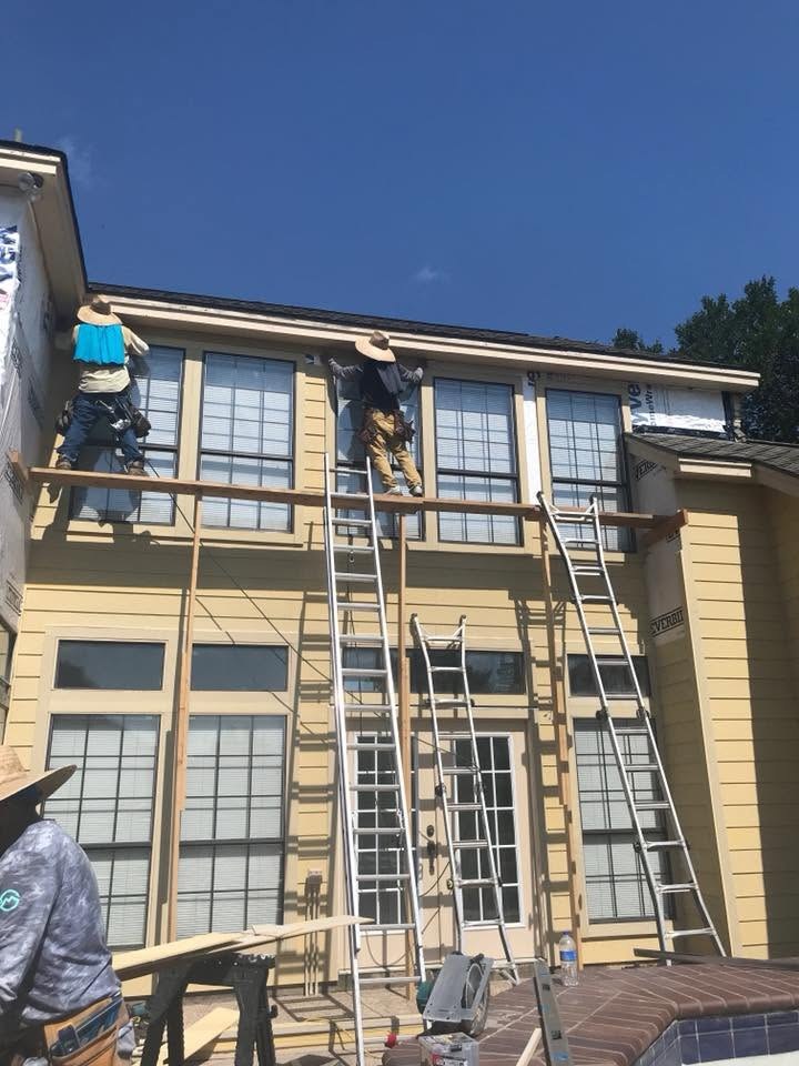 Crew on scaffolding installing siding on a two-story multi-family building