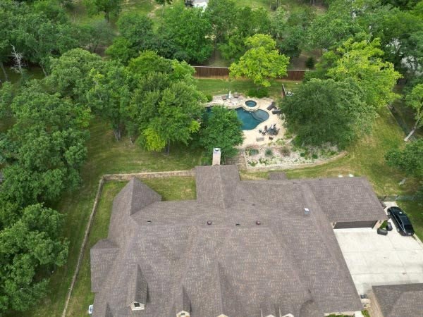 Aerial inspection view of a large residential roof surrounded by trees